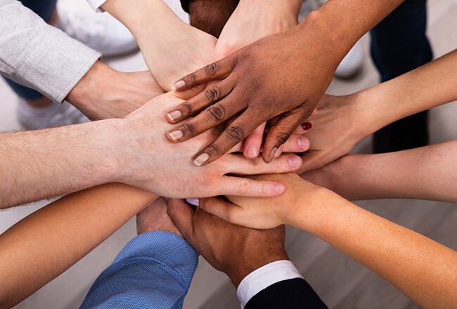 A diverse group of hands stacked together, symbolizing teamwork, unity, and cooperation.