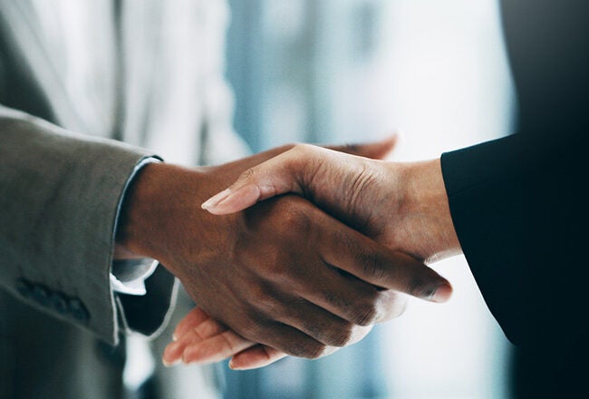 Two people shaking hands, symbolizing agreement or partnership in a business setting.