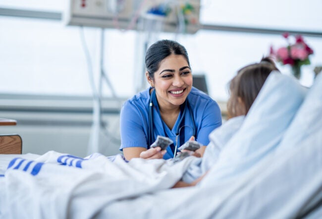 Nurse smiling at a patient in a hospital bed as an example of empathy in healthcare